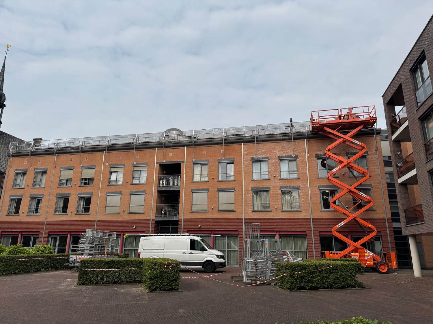 Zonnepanelen op het dak van een appartementencomplex, geplaatst met een schaarlift