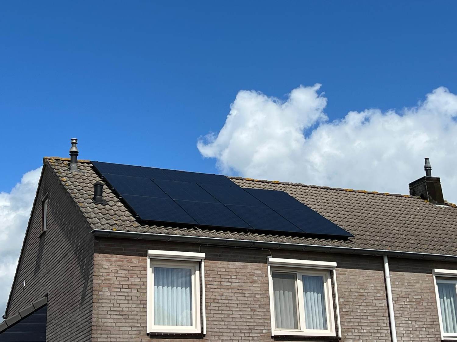 Woning met zonnepanelen tegen een blauwe lucht
