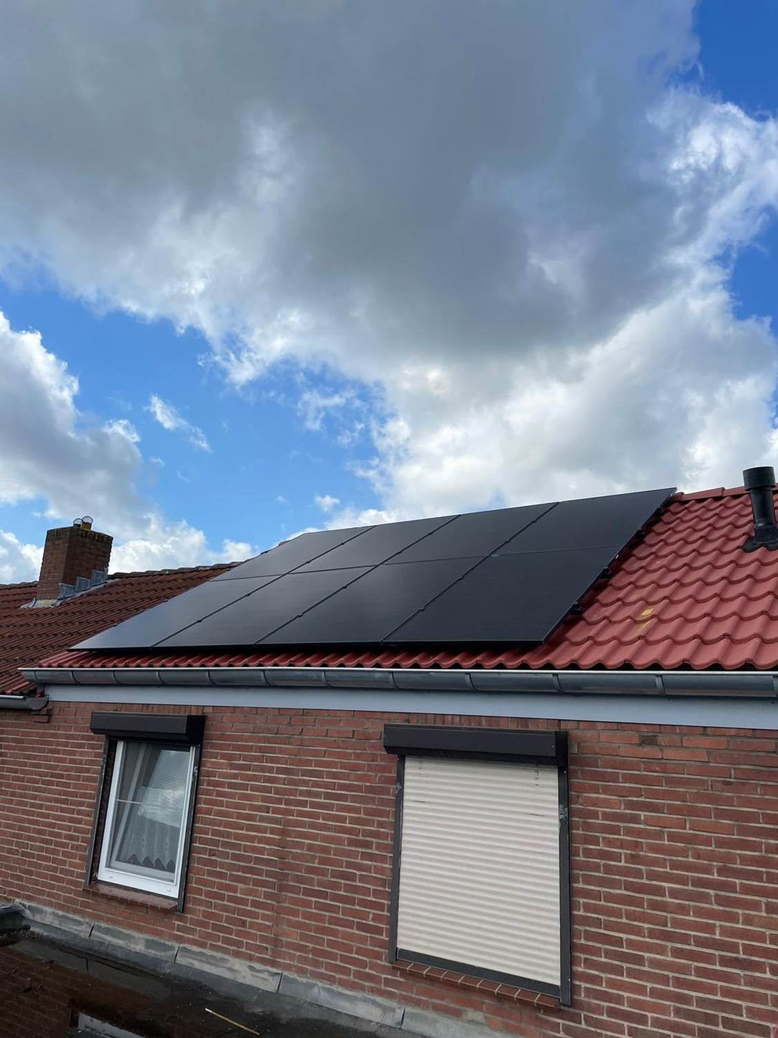 Zwarte zonnepanelen op een rood pannendak
